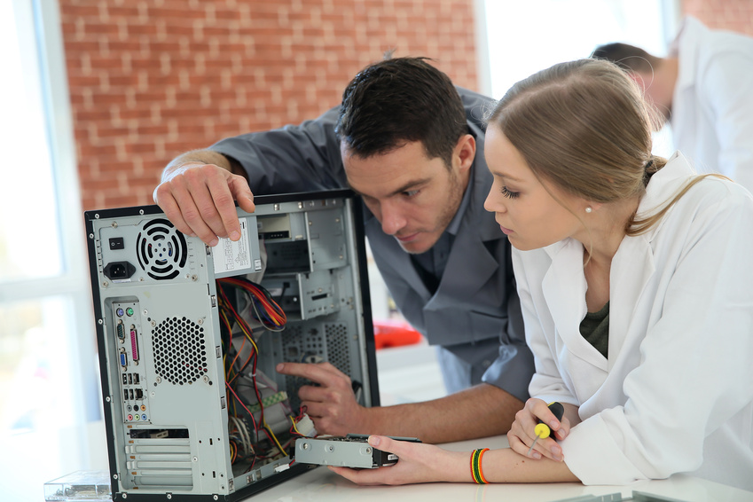 Teacher with student in technology repairing computer
